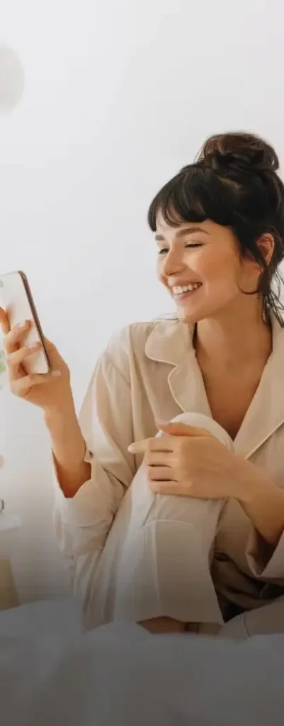 Smiling woman looking at her phone while sitting at home